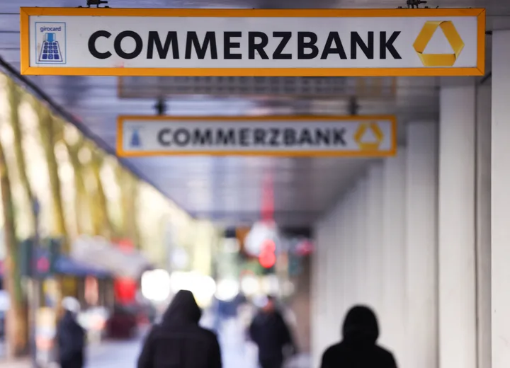 Sediul Commerzbank, cu oameni care trec pe lângă, simbolizând restructurarea bancară.