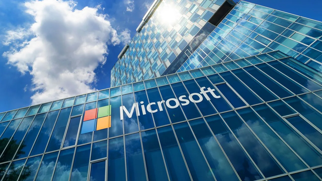 Sediul Microsoft reflectat în geamuri, sub un cer cu nori.