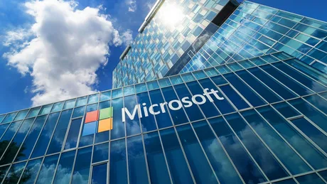 Sediul Microsoft reflectat în geamuri, sub un cer cu nori.