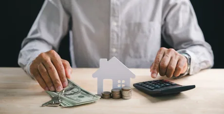 Persoană analizând costurile financiare cu bani și un calculator.