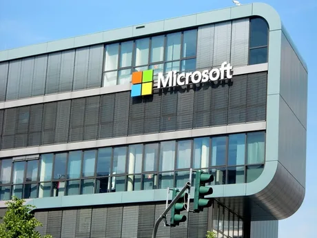 Clădirea Microsoft cu logo-ul companiei pe fațadă, sub un cer senin.