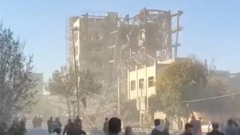 Clădire distrusă în urma atacului din Qom, cu oameni în jur.