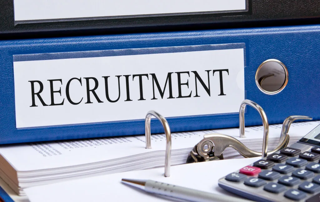 Dosar de recrutare cu documente și un calculator pe birou.