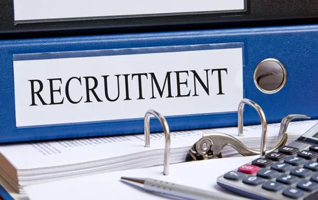 Dosar de recrutare cu documente și un calculator pe birou.