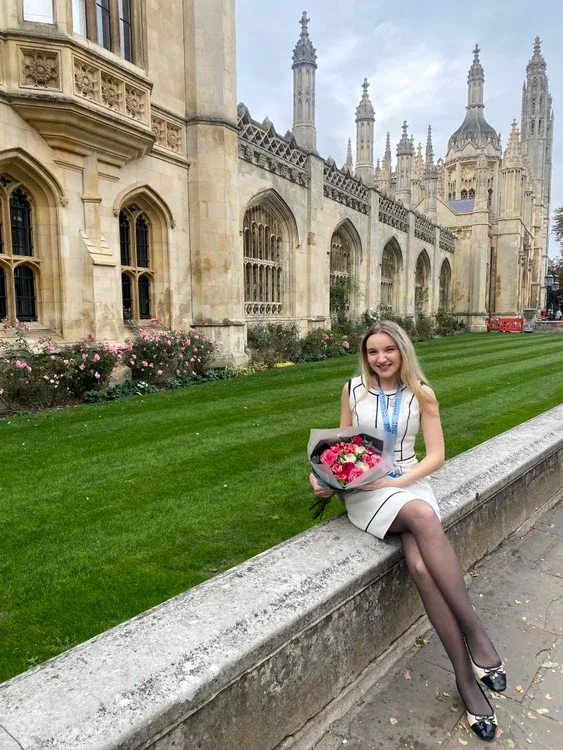 Lisa-Maria Tănase la Cambridge, cu flori, în fața clădirii istorice.