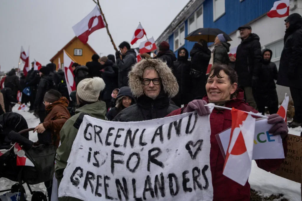Protestatari cu steaguri și pancarte în Nuuk.