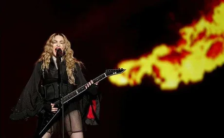 Madonna cântând pe scenă, cu o chitară electrică în mână.
