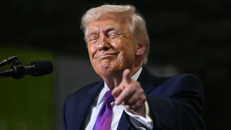 Donald Trump zâmbind și arătând cu degetul spre cameră.