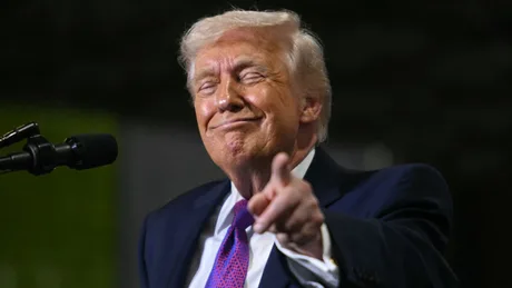 Donald Trump zâmbind și arătând cu degetul spre cameră.