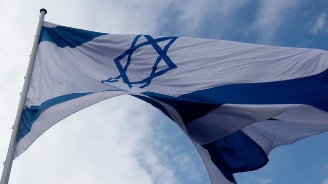 Steag israelian fluturând sub un cer senin, simbol al tensiunilor din regiune.
