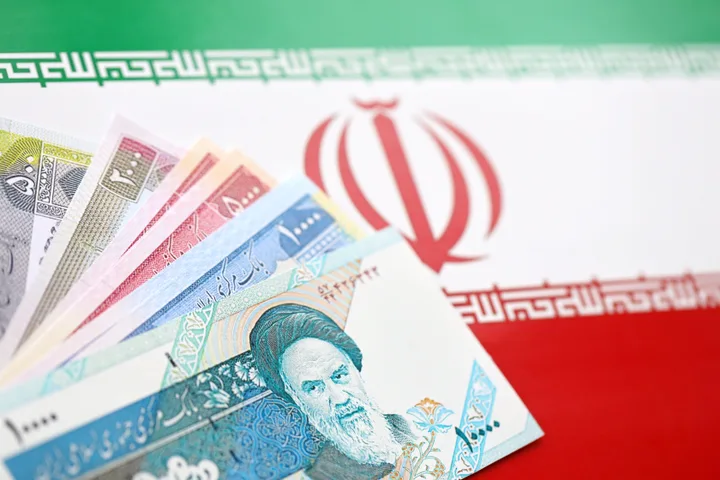 Bancnote iraniene pe fundalul steagului național al Iranului.