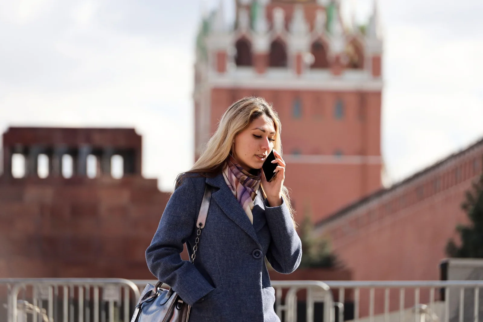 Femeie vorbind la telefon în fața unei clădiri istorice din Rusia.