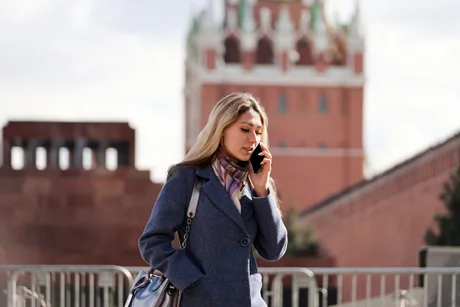 Femeie vorbind la telefon în fața unei clădiri istorice din Rusia.