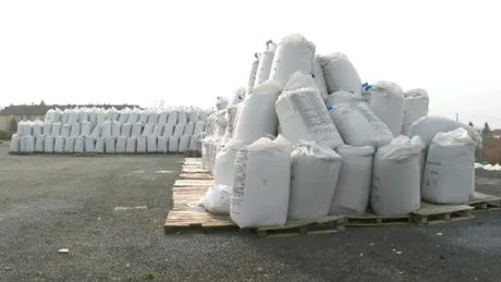 Stive de saci cu îngrășăminte pe un teren agricol vast.