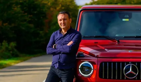 Antreprenorul turc din Iași, Ibrahim Gunbeyi, lângă o mașină roșie.