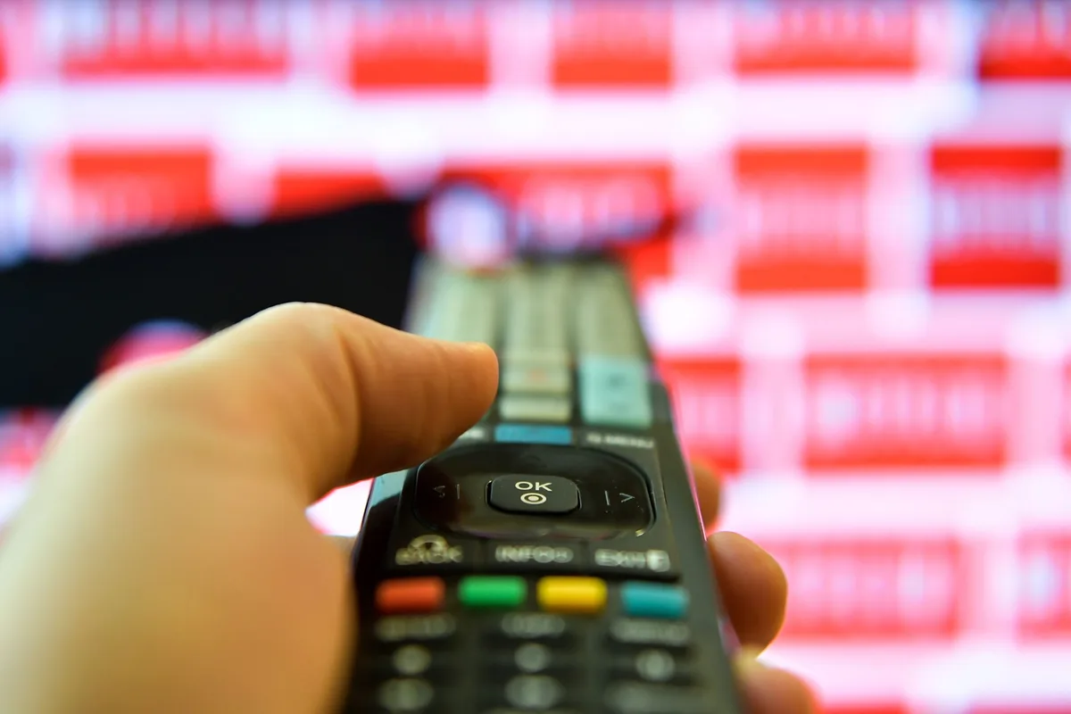 Telecomandă îndreptată spre un ecran cu conținut video diversificat