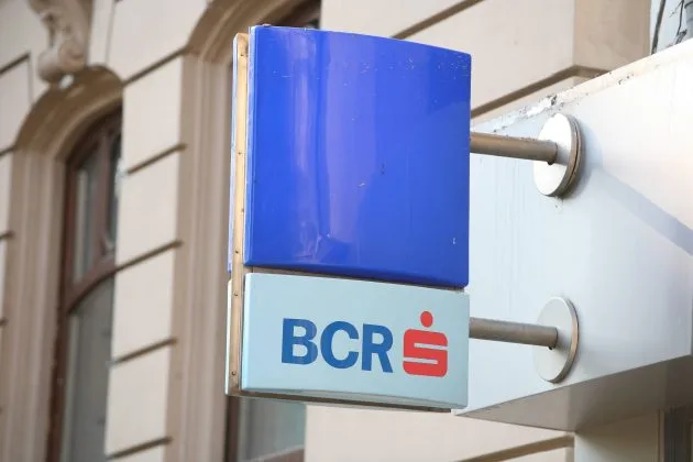 Logo-ul BCR pe fațada unei clădiri, simbolizând activitatea bancară.