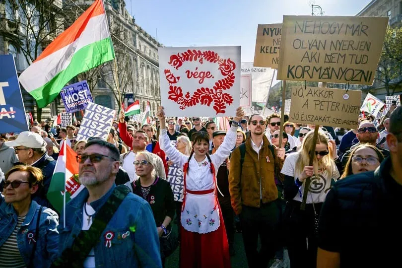 Oamenii protestează în stradă, purtând pancarte și steaguri ungare.