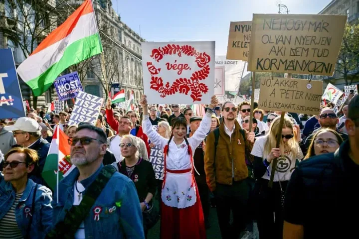 Oamenii protestează în stradă, purtând pancarte și steaguri ungare.