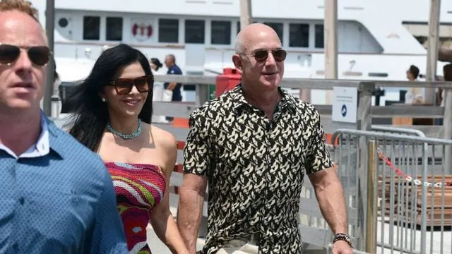 Jeff Bezos și o femeie, plimbându-se pe o promenadă aglomerată.