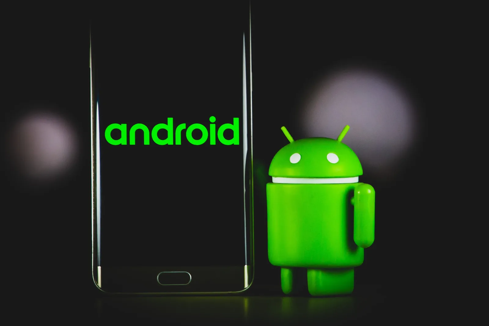 Logo Android și figurina verde a robotului Android pe fundal întunecat.