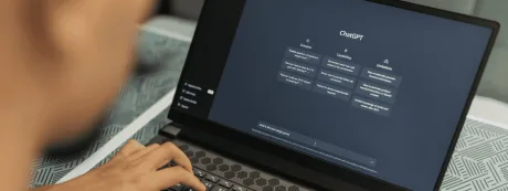 Utilizator lucrând pe laptop cu ChatGPT deschis pe ecran.