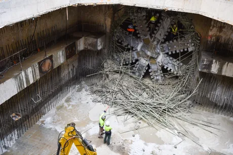 Lucrări de construcție pentru metrou, cu muncitori și echipamente în șantier.