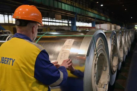 Un angajat verifică documentele pe role de metal în fabrică.