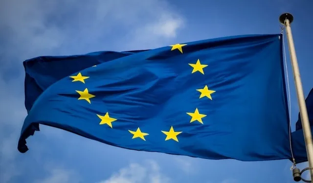 Steagul Uniunii Europene fluturând în vânt, simbol al cooperării europene.