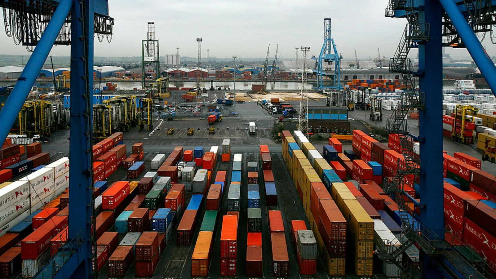 Vedere generală a unui port cu containere colorate și echipamente de transport.