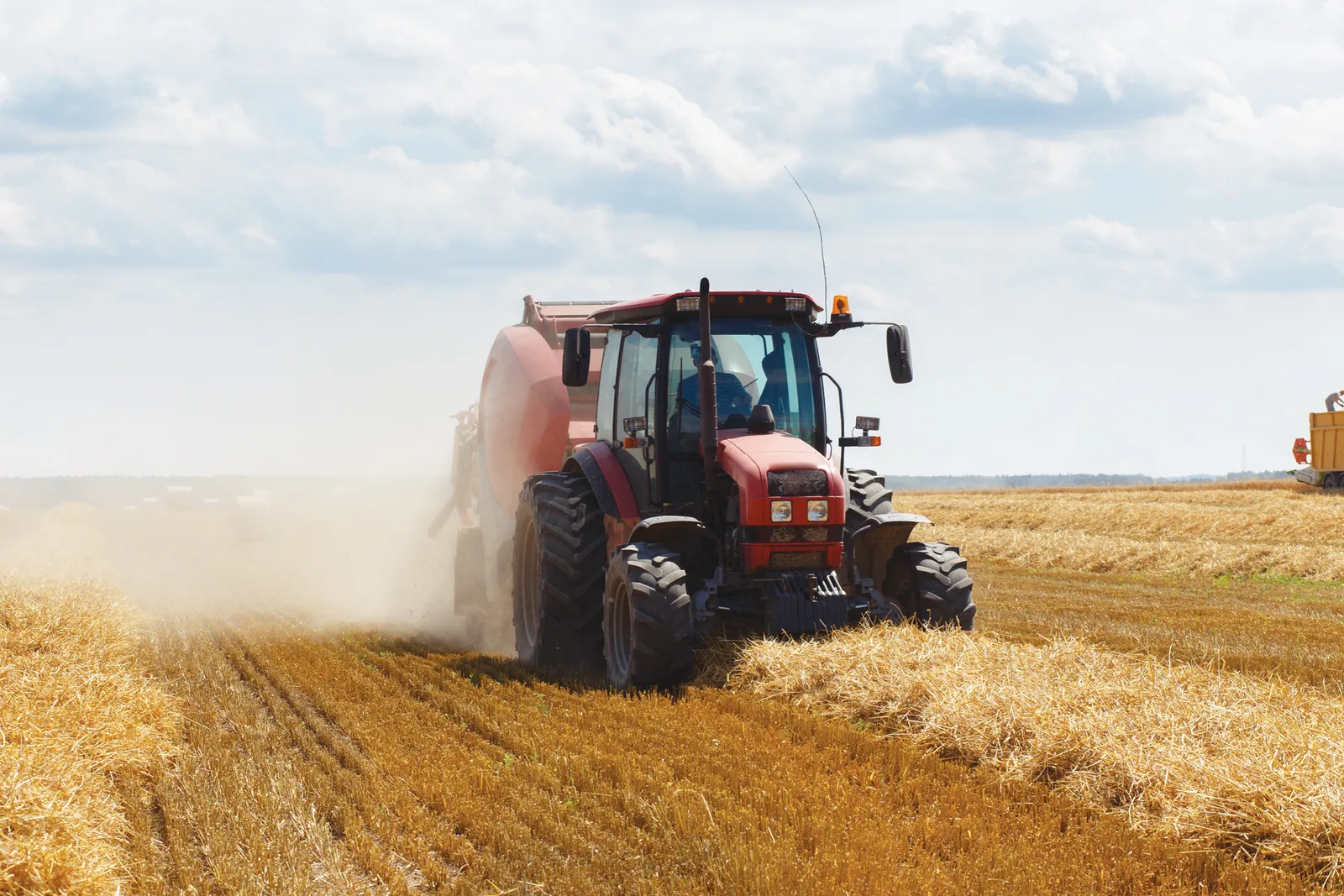 Tractor lucrând pe câmpuri agricole în timpul recoltării.
