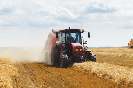 Tractor lucrând pe câmpuri agricole în timpul recoltării.