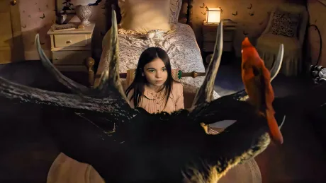 O fetiță privind cu uimire un extraterestru în camera ei întunecată.