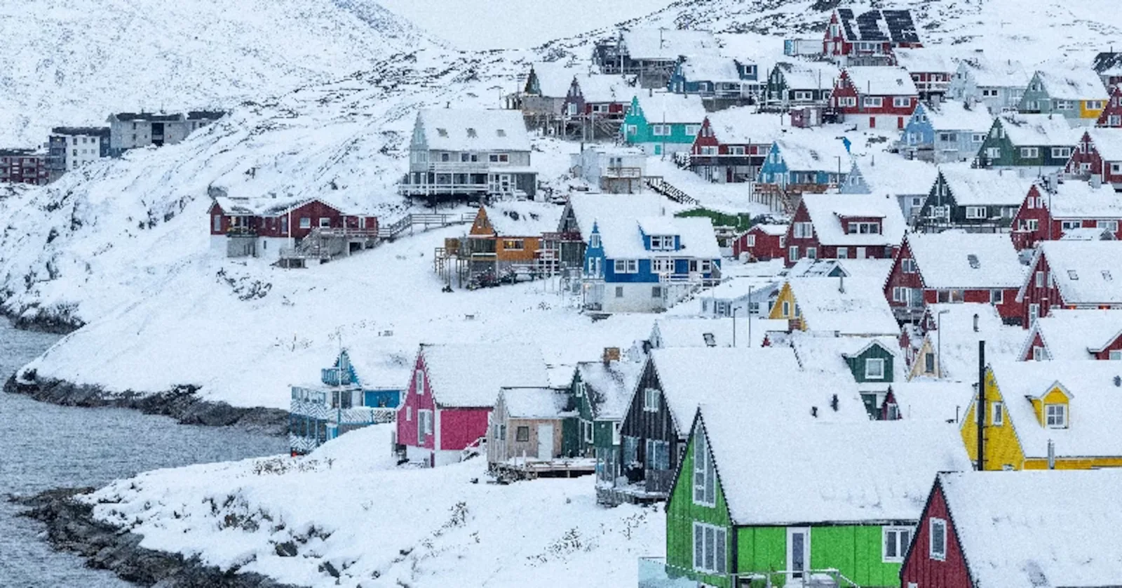 Peisaj urban din Nuuk, Groenlanda, acoperit de zăpadă și case colorate.