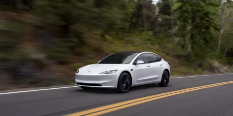 Mașină electrică pe drum, evidențiind tendințele de prețuri în scădere.