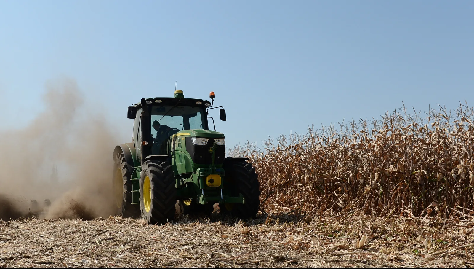 Tractor lucrând pe câmp, pregătind terenul pentru subvenții agricole.