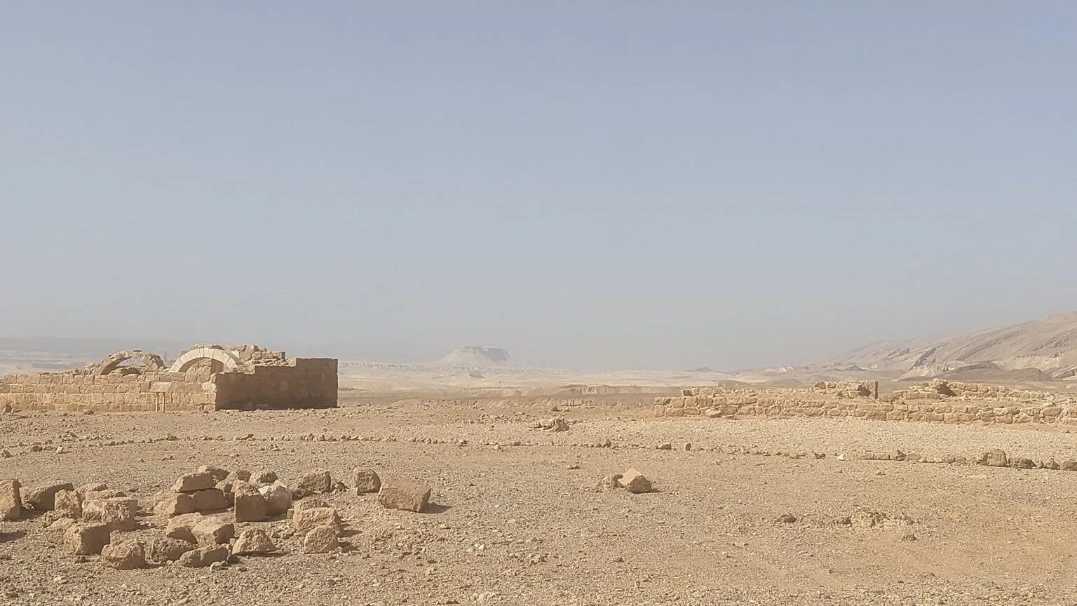 Peisaj arid în deșertul Irakului, cu ruine și stânci vizibile.