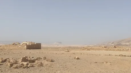 Peisaj arid în deșertul Irakului, cu ruine și stânci vizibile.