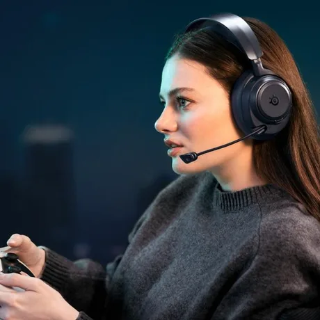 Tânără jucătoare folosind căști wireless pentru gaming, concentrată pe ecran.