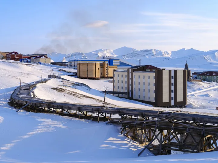 Peisaj din Barentsburg, cu clădiri și zăpadă în jur.