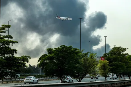 Avion zburând deasupra unui peisaj afectat de fum și conflicte.