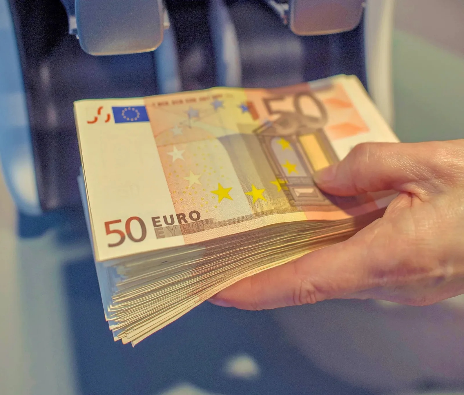 Bancnote de 50 de euro în mână, simbolizând plățile cash.
