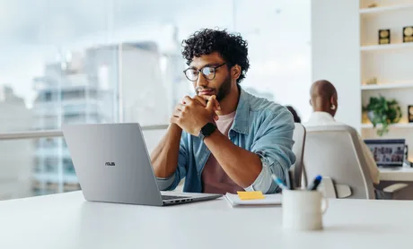 Un profesionist lucrează la un laptop ASUS într-un mediu de birou modern.