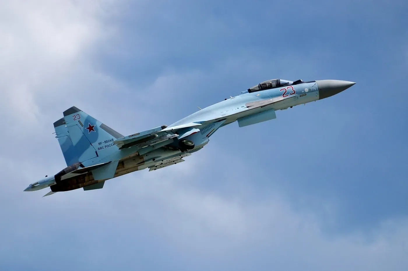 Avion de luptă rus în zbor, cu cer albastru în fundal.