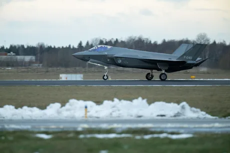 Avion F-35 decolând pe o pistă acoperită cu zăpadă.