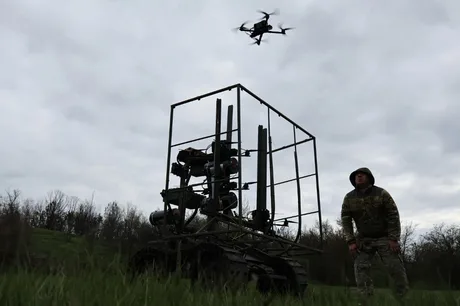 Un pilot de drone în timpul antrenamentului, cu un aparat zburător în fundal.
