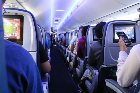 Interiorul unui avion cu pasageri așezați pe scaune, în așteptarea zborului.