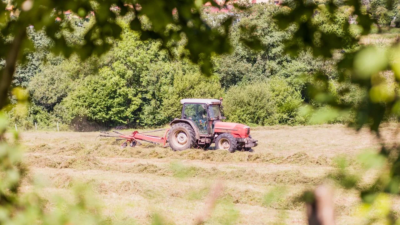 Tractor pe câmp, lucrând pajiștea pentru recoltă.