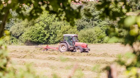 Tractor pe câmp, lucrând pajiștea pentru recoltă.