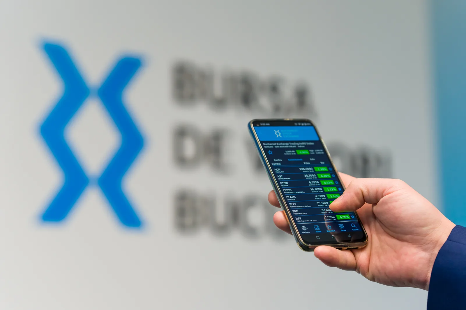 Un investitor analizează acțiunile pe telefonul mobil la Bursa de Valori București.